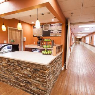 A modern reception area featuring a cafe with wooden flooring and warm lighting.