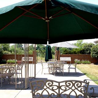 A serene outdoor patio area featuring metal furniture and a green umbrella.