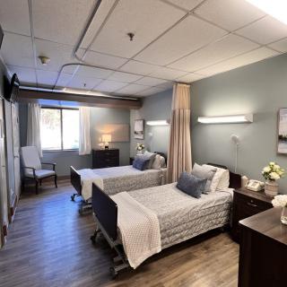 A hospital room with two neatly made beds and soft lighting.