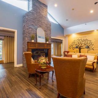 A cozy living room with a fireplace, comfortable armchairs, and decorative wall art.