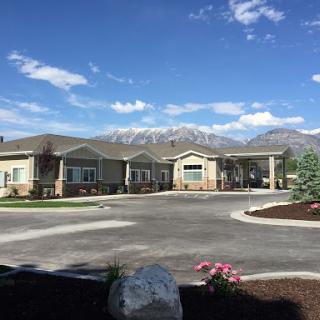 A serene residential building surrounded by mountains and a clear blue sky.