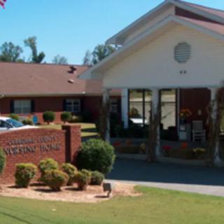 Entrance to a nursing home with a sign and landscaped surroundings.