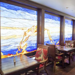 A cozy restaurant interior featuring vibrant stained glass windows and comfortable seating.