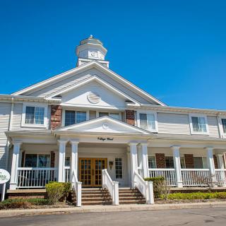 A large white building with a porch and multiple windows under a clear blue sky.