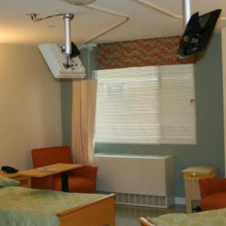A hospital room with beds, chairs, and medical equipment.