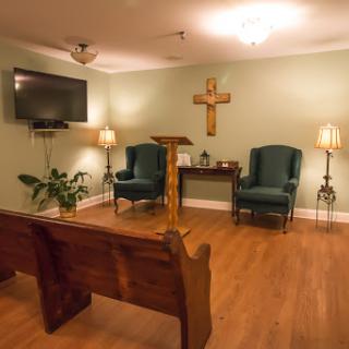 A peaceful chapel interior featuring wooden benches, a podium, and soft lighting.