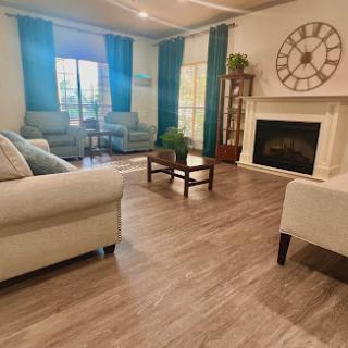 A cozy and stylish living room featuring light-colored furniture, a decorative fireplace, and vibrant blue curtains.