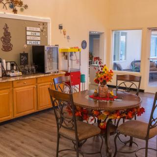 A cozy dining area with autumn-themed decorations, featuring a coffee station and popcorn machine.