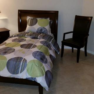 A neatly arranged bedroom with a bed and a chair.