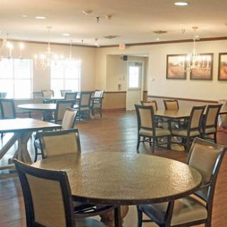 A cozy dining area with round tables and chairs, illuminated by chandeliers.