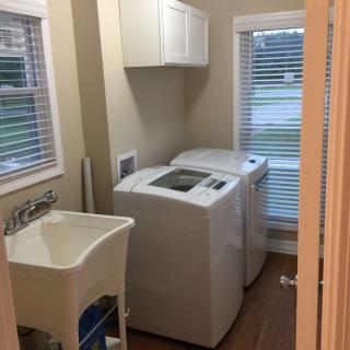 A compact laundry room with a washing machine, dryer, and utility sink.