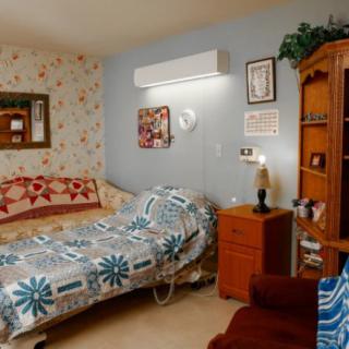A cozy bedroom with a quilted bed, wooden furniture, and decorative wall art.