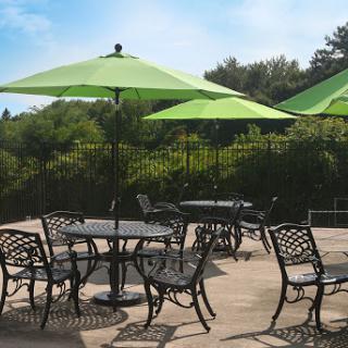 A serene outdoor patio setup with green umbrellas and elegant furniture, perfect for enjoying sunny days.