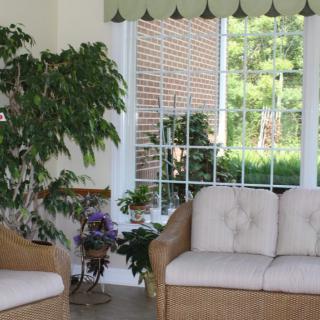 A cozy living room with wicker furniture and large windows letting in natural light.
