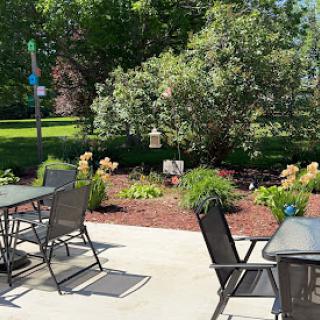 A serene outdoor patio area with seating surrounded by lush greenery and vibrant flowers.