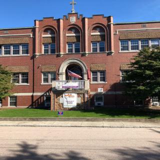 A historic brick building with symmetrical windows and an American flag displayed at the entrance.