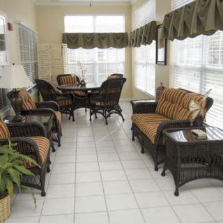 A cozy sunroom with wicker furniture and ample natural light streaming through large windows.
