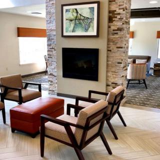 A modern lobby with comfortable seating and a central fireplace.