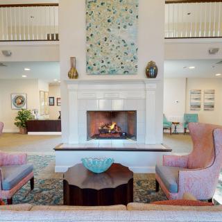A cozy living room with a fireplace, armchairs, and decorative elements.