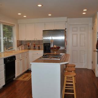 A modern kitchen with white cabinets, an island, and stainless steel appliances.