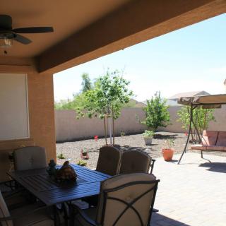 A covered patio with furniture overlooking a desert-themed backyard.