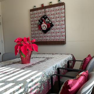 A beautifully decorated dining room with a festive table setting, featuring a poinsettia centerpiece and a holiday wreath on the wall.