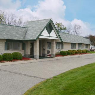 A well-maintained single-story building surrounded by a neatly trimmed lawn and a clear blue sky.