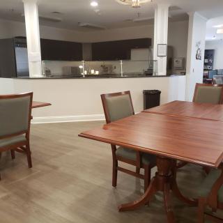 Spacious dining area with wooden tables and chairs, adjacent to a modern kitchen.