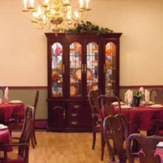 A warmly decorated dining room with a chandelier and china cabinet.