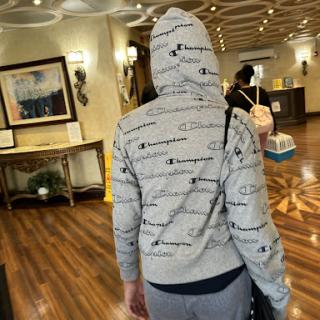 A person wearing a patterned hoodie stands in a hotel lobby.