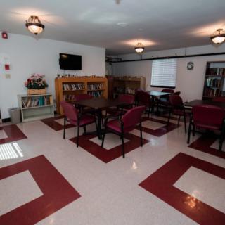 A community room with seating arrangements, bookshelves, and a television.