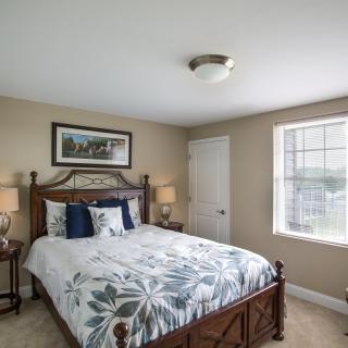 A cozy bedroom featuring a large bed with patterned bedding, two bedside lamps, and a window letting in natural light.