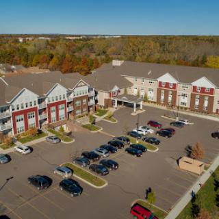 Aerial view of a commercial building with a spacious parking lot, surrounded by autumn foliage.