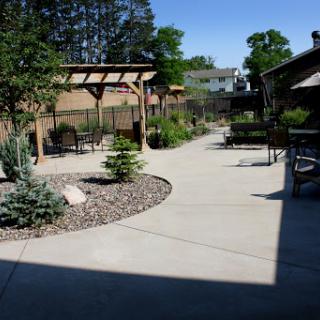 A serene outdoor space featuring a winding pathway surrounded by greenery and seating areas.