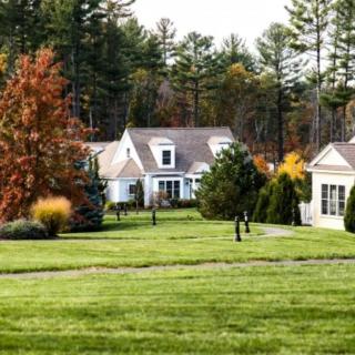 A suburban home with a well-maintained lawn and colorful autumn trees.