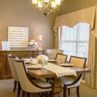 A warmly decorated dining room with a wooden table, cushioned chairs, and elegant lighting.