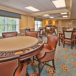 A well-lit game room featuring a poker table and chairs, with windows allowing natural light to enter.