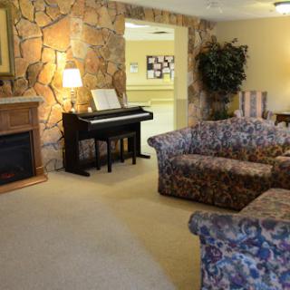 A cozy living room featuring floral-patterned sofas, a piano, and a decorative stone wall.