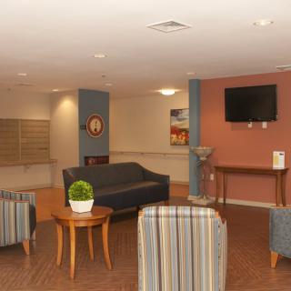 A cozy lobby area with seating, a television, and a small plant on a table.
