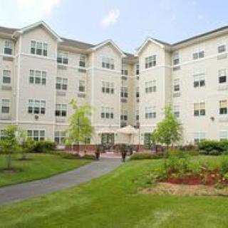 A multi-story residential apartment building with a landscaped garden and pathway in the foreground.