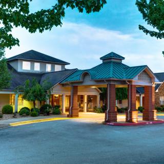 A hotel entrance with a well-lit canopy surrounded by trees during the evening.