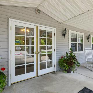 A welcoming entrance with glass double doors, potted plants, and a covered porch.