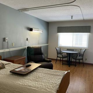 A hospital room with a bed, chair, and a small table by the window.
