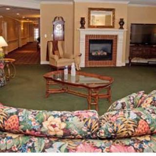 A cozy living room with floral sofas, a fireplace, and a large television.
