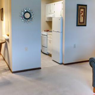 A cozy apartment interior featuring a view into the kitchen with white cabinets and appliances.