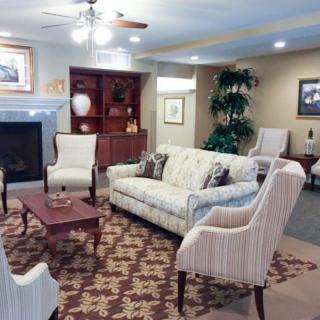 A cozy living room with elegant furnishings, including a sofa, chairs, and a coffee table, arranged around a fireplace.