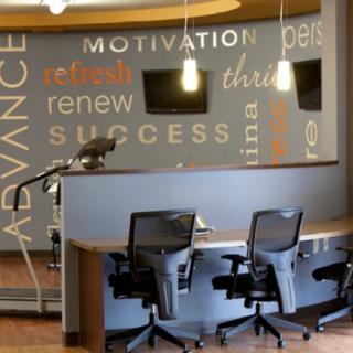 A modern office reception area with motivational words on the wall and sleek chairs.