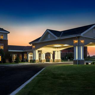 An illuminated hotel entrance at dusk, showcasing elegant architecture against a sunset backdrop.