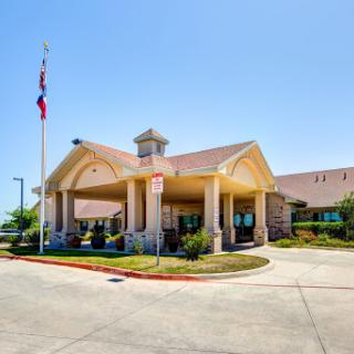 Welcoming hotel entrance with landscaped surroundings and flags.