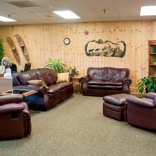 A cozy lobby with leather sofas, rustic wood paneling, and decorative elements.